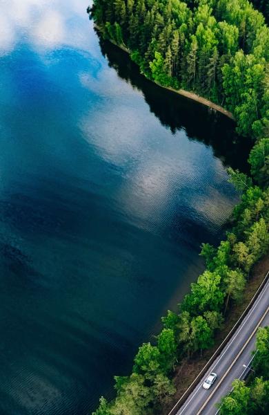 Aerial view of a road winding through a forest and a lake
