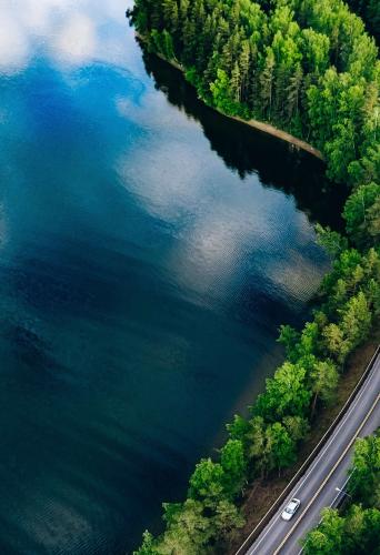 Aerial view of a road winding through a forest and a lake